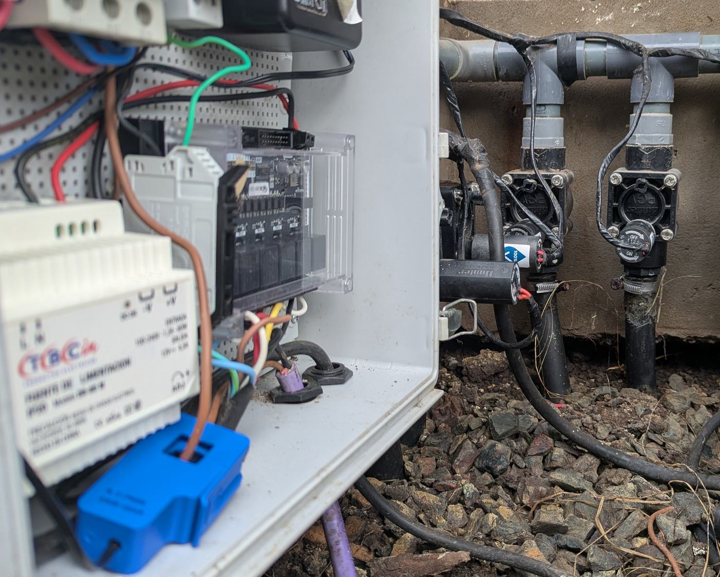 Hornero instalado a la intemperie: gabinete abierto con el controlador, la fuente de 24 VAC y la protección eléctrica, junto al colector de válvulas del riego